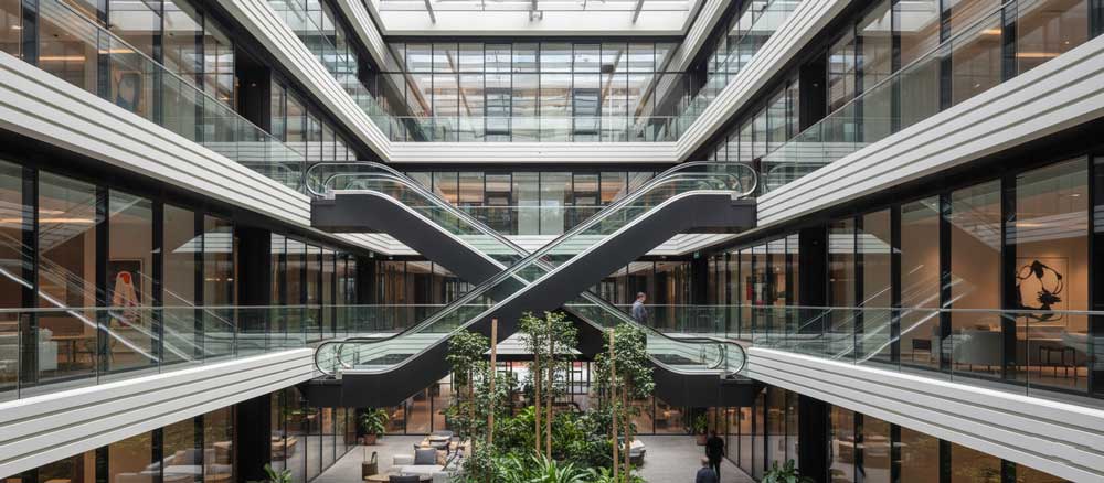 نمای داخلی یک ساختمان مدرن با پله برقی مسکونی شیشه‌ای و طراحی لوکس